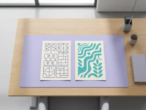 Zwei elegante Dokumente auf Holzschreibtisch: eines mit blauen geometrischen Mustern, eines mit türkisfarbenen organischen Formen